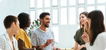 Group of young coworkers standing around a desk