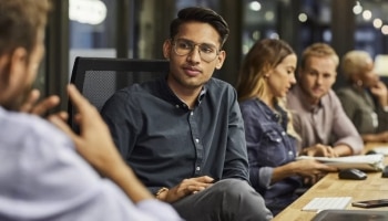 Man sitting at table listening to another person speaking.