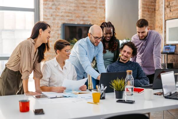 group of coworkers leaning in to a laptop in an office