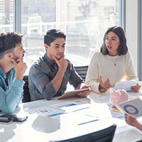 Business professionals sitting around a conference table collaborating in a conference room surrounded by windows