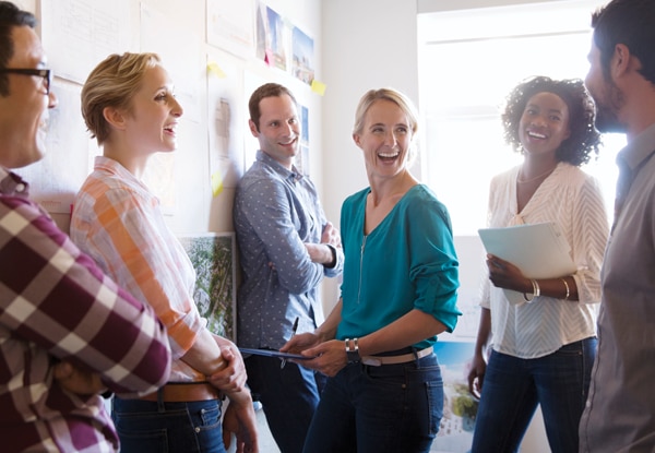 A group of people standing in a conference room laughing