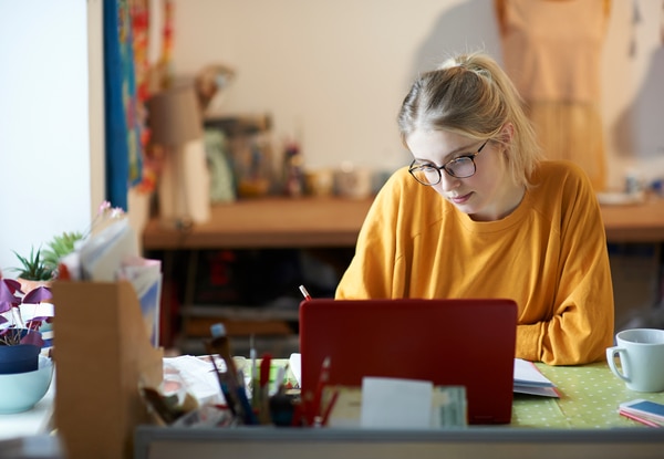 Young blonde woman working at her home desk.